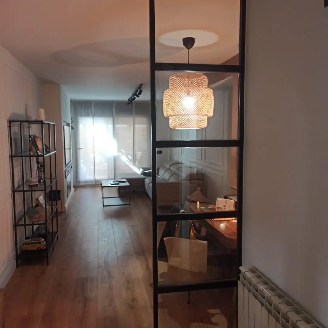 Una sala de estar con una mampara de cristal y una lámpara colgando del techo.