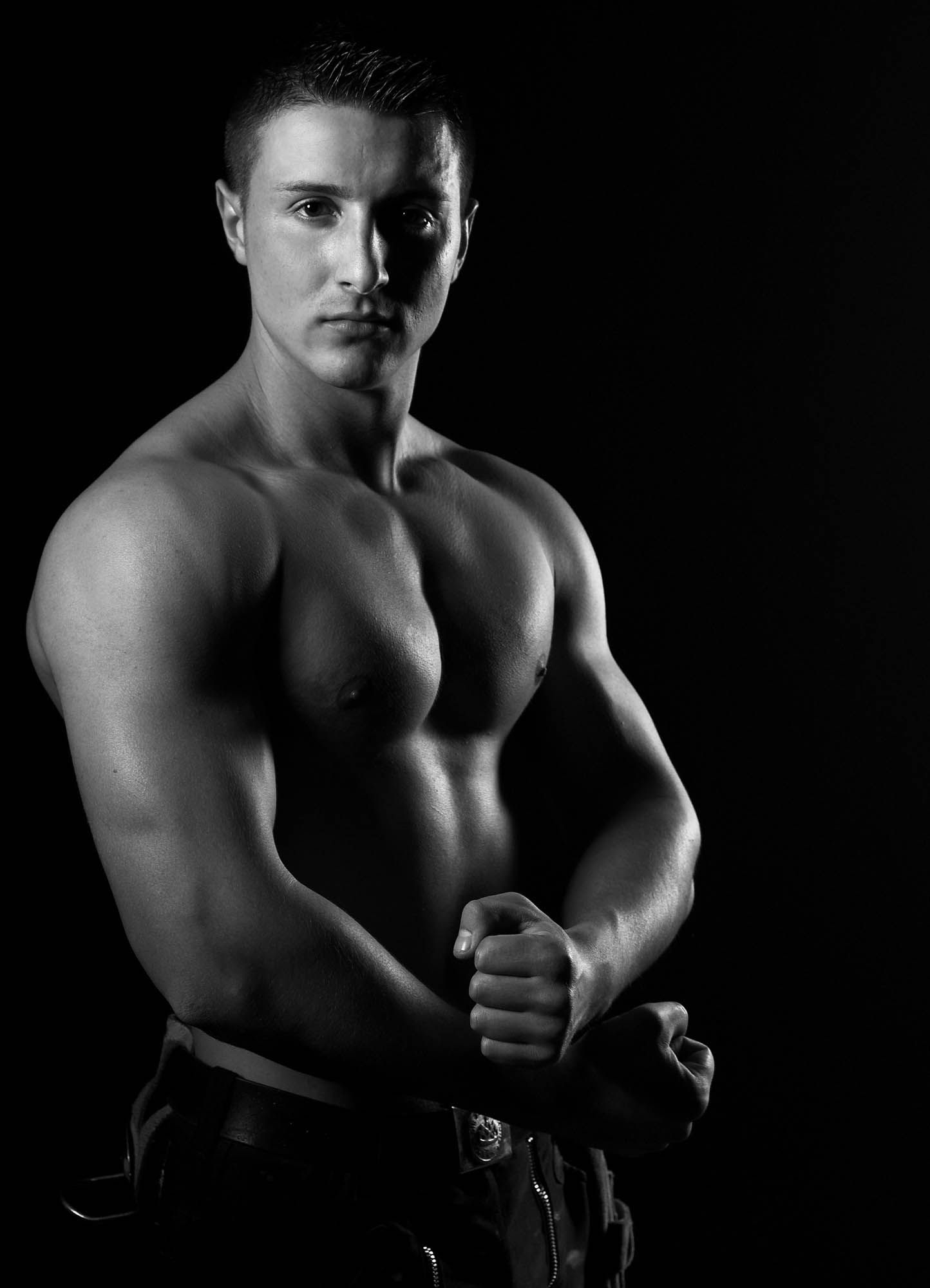 Ein Schwarzweißfoto eines Mannes ohne Hemd mit verschränkten Armen