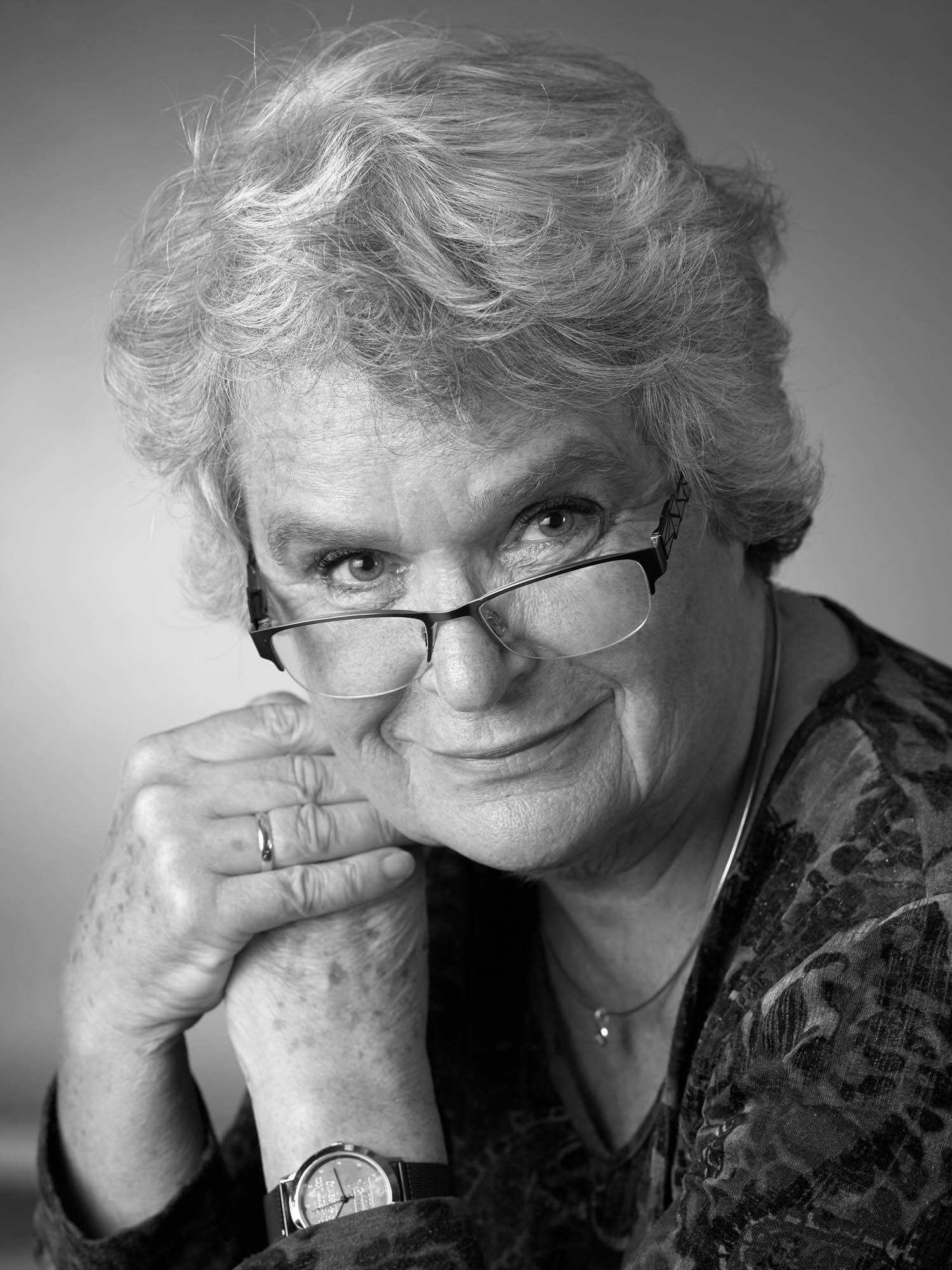 Ein Schwarzweißfoto einer Frau mit Brille und Uhr.