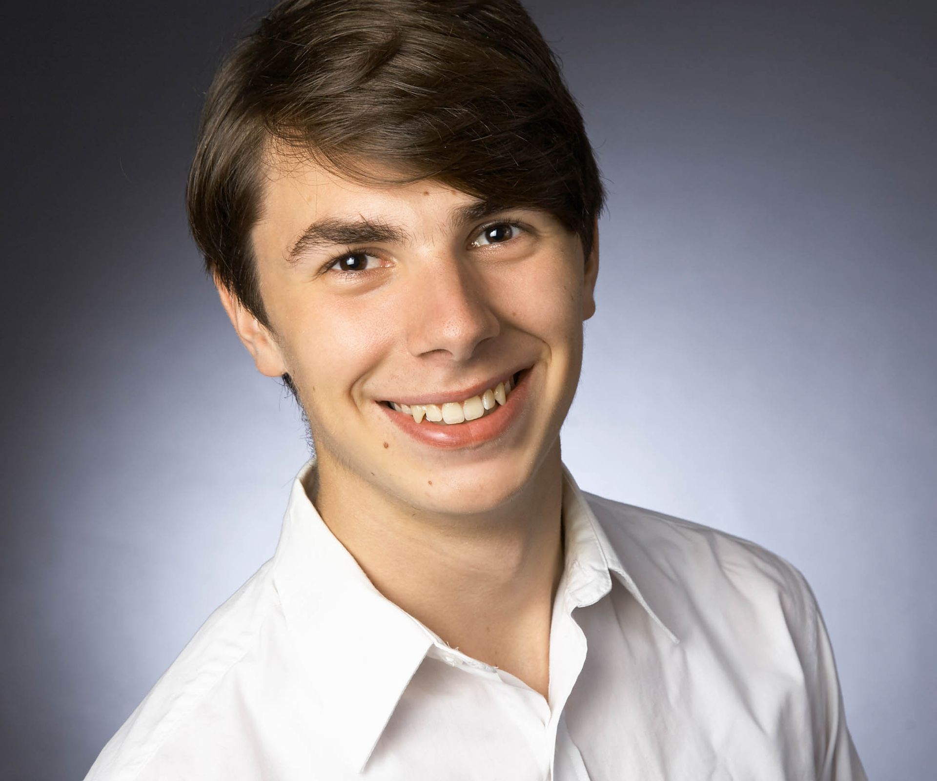 Ein junger Mann in einem weißen Hemd lächelt in die Kamera