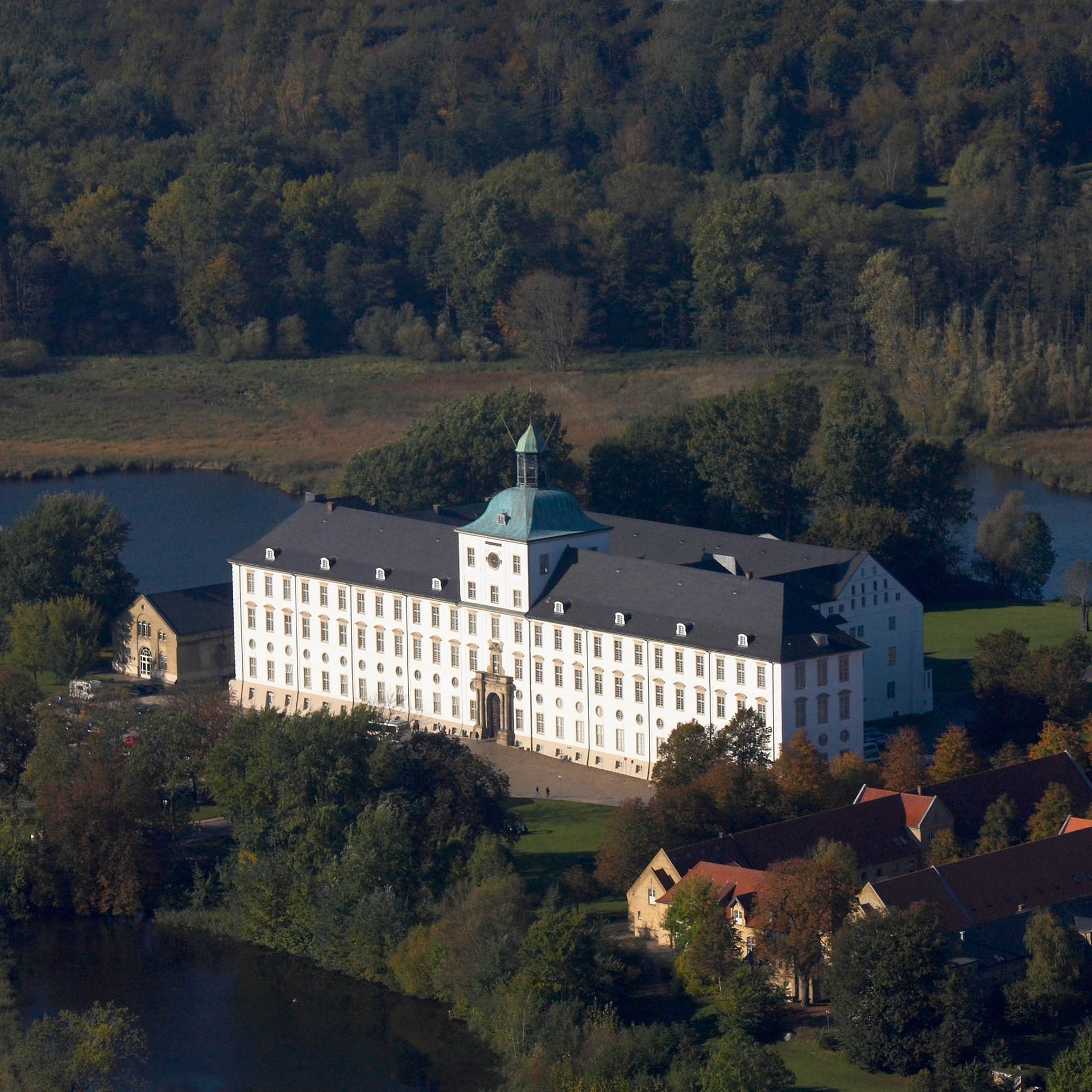 Eine Luftaufnahme eines großen weißen Gebäudes, umgeben von Bäumen und einem Fluss