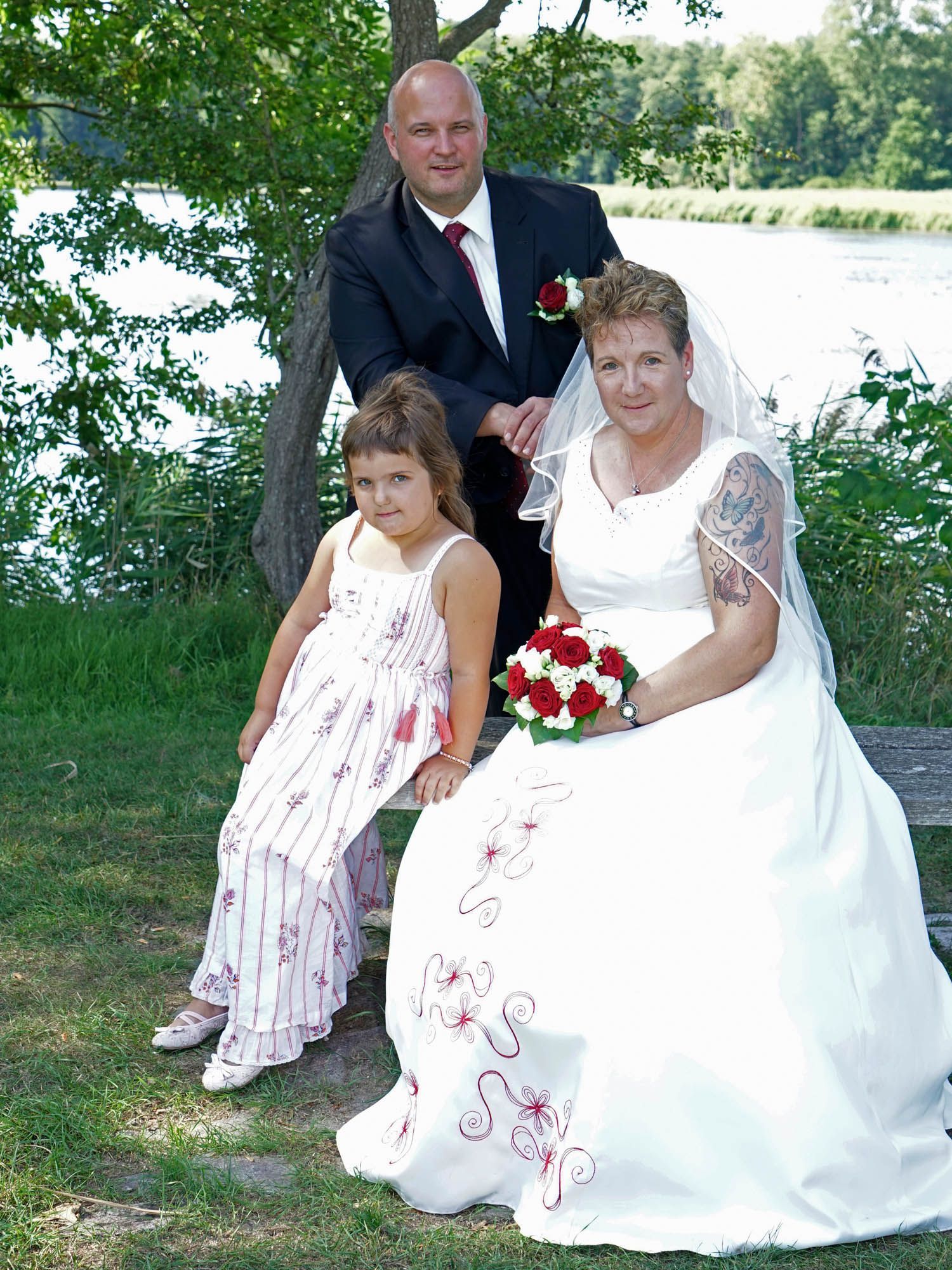 Braut und Bräutigam posieren mit ihrer Tochter für ein Foto.