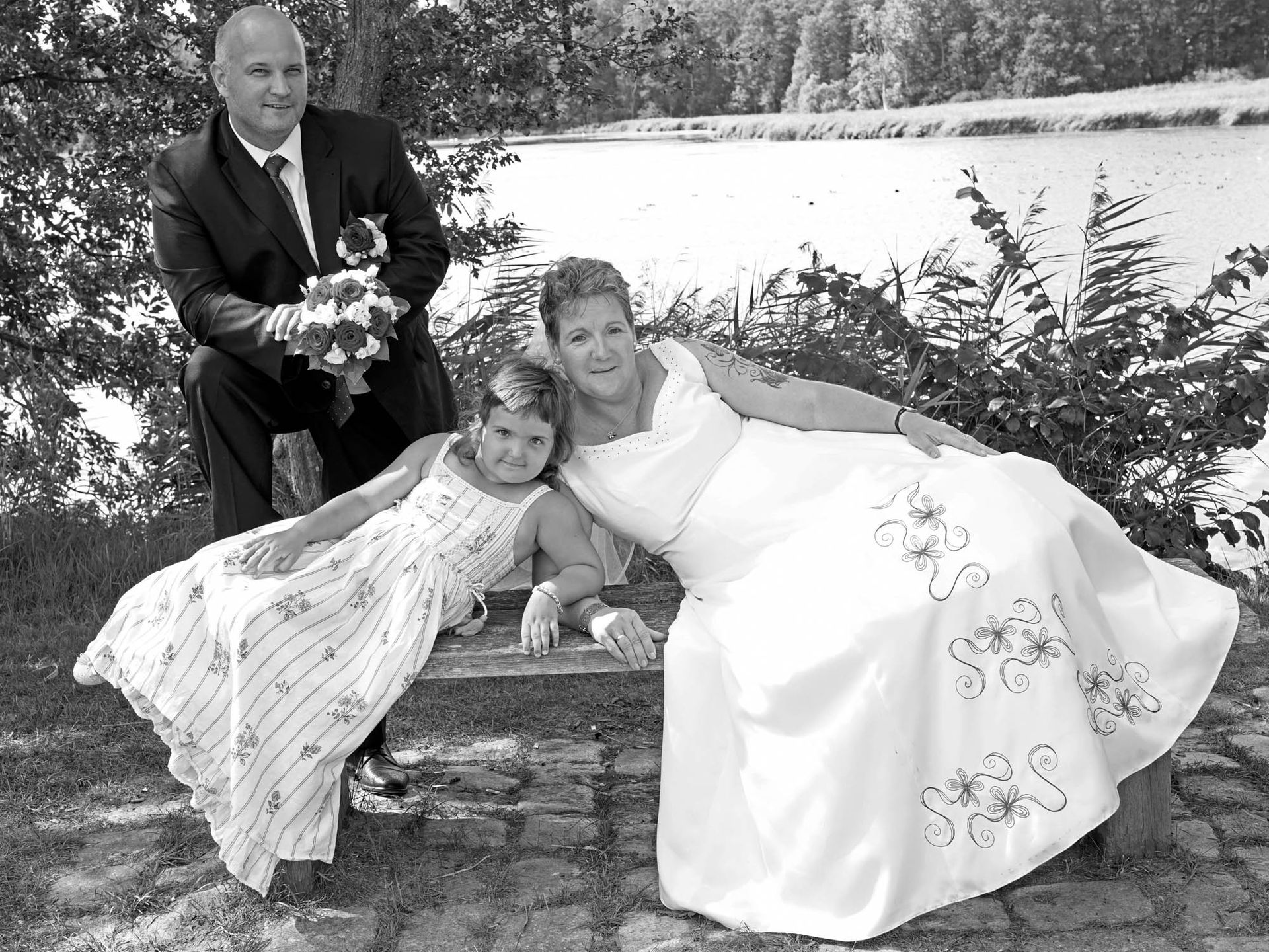 Ein Schwarzweißfoto von Braut und Bräutigam, die mit ihrer Tochter posieren