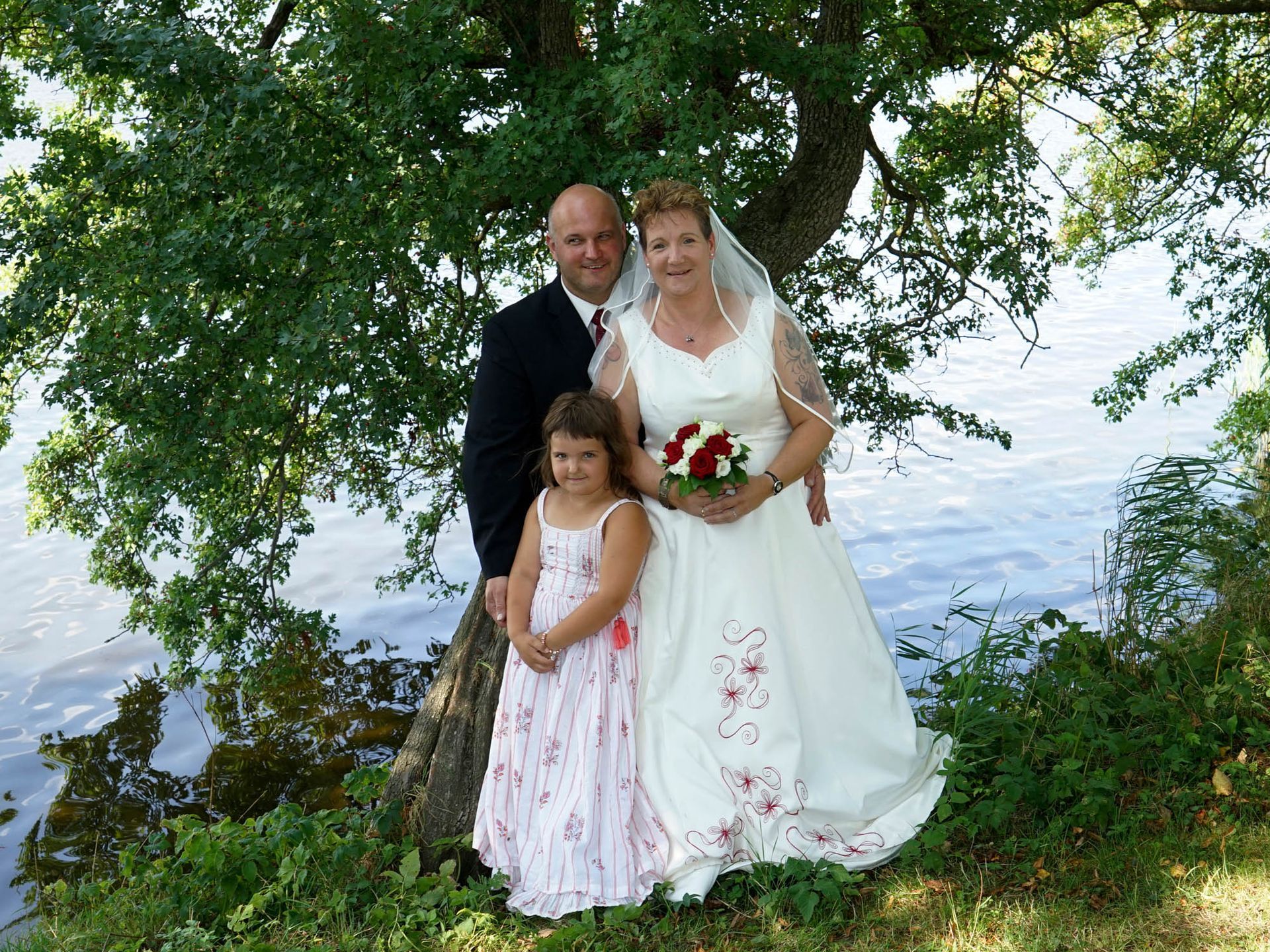 Braut und Bräutigam posieren für ein Foto mit ihrer Tochter