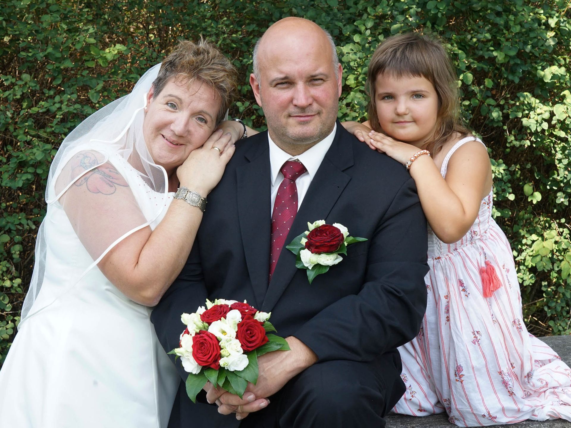 Braut und Bräutigam posieren für ein Foto mit ihrer Tochter