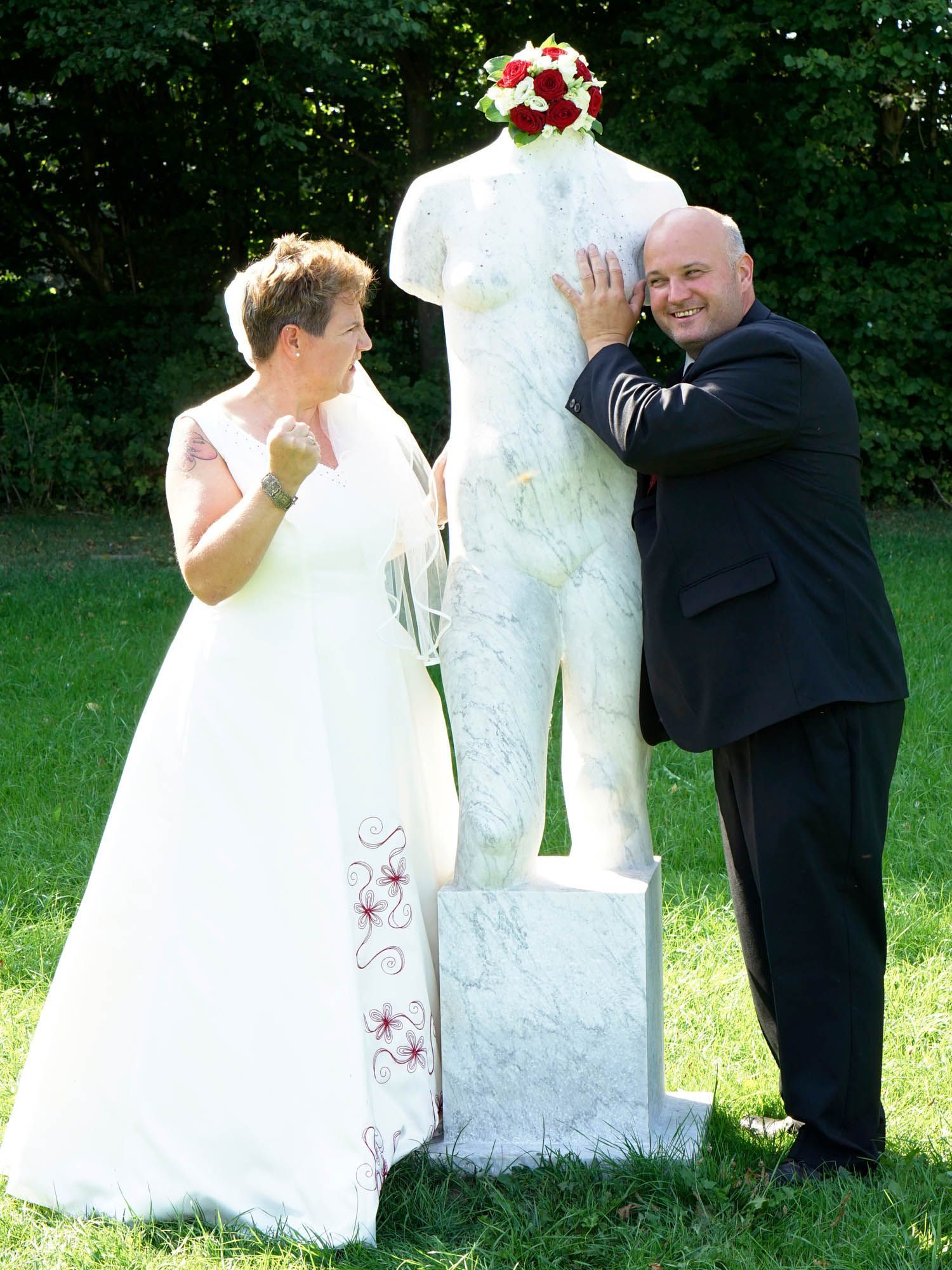 Eine Braut und ein Bräutigam stehen neben einer Frauenstatue