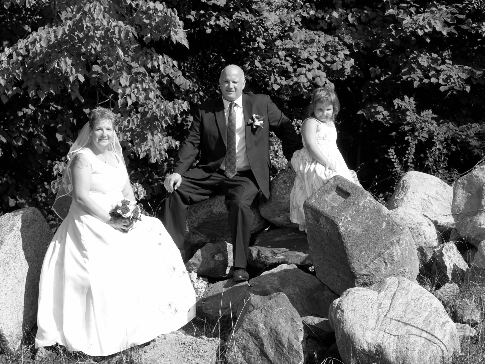 Ein Schwarzweißfoto von Braut und Bräutigam, die auf Felsen sitzen