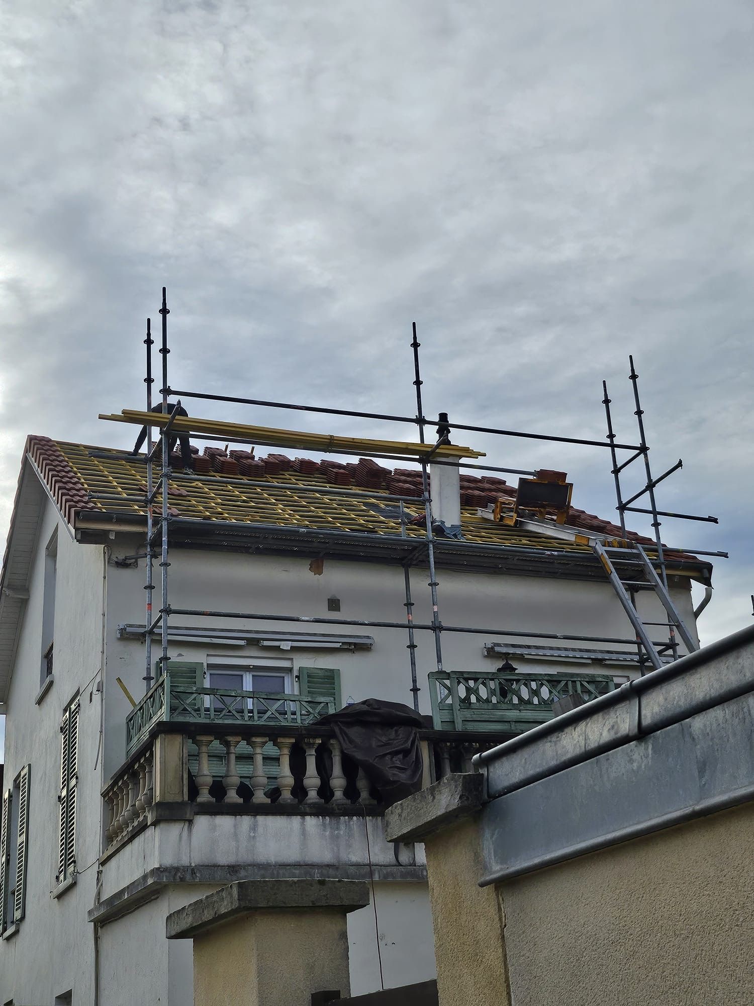 Maison avec échafaudages et travaux de toiture sous un ciel nuageux