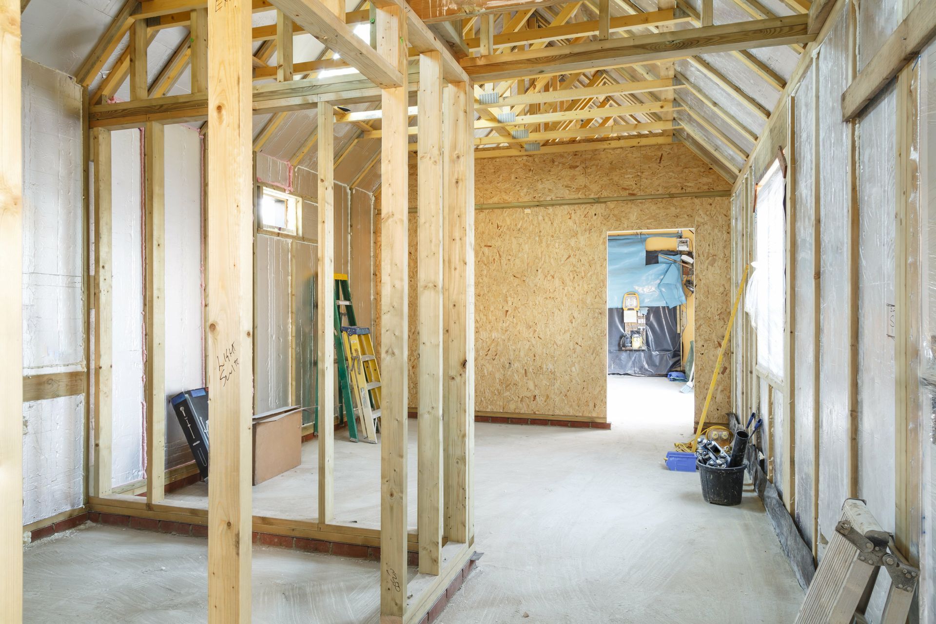 Intérieur d'une maison en construction avec charpente apparente et murs non finis