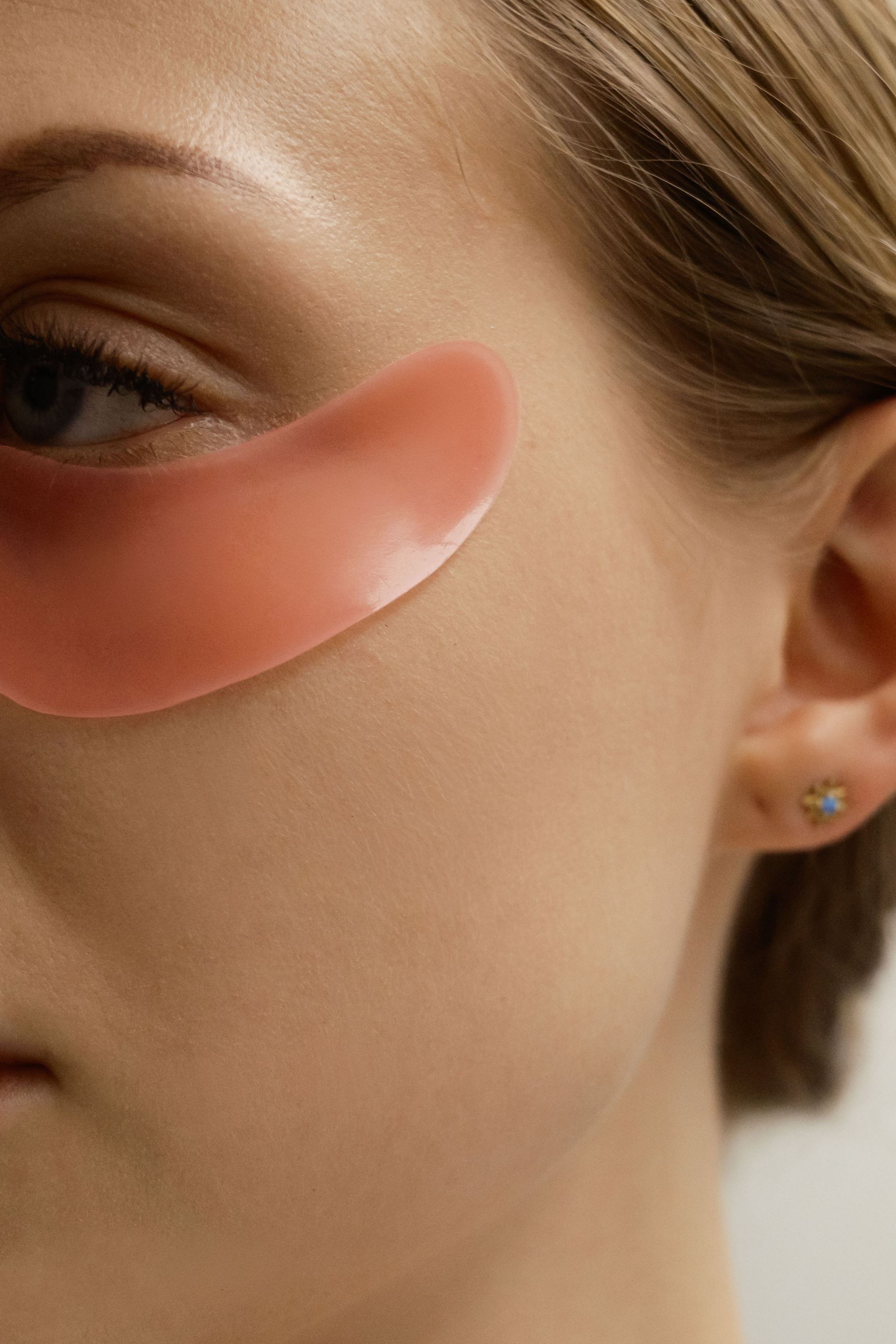 Gros plan d'un visage avec un patch rose sous l'œil, sur la pommette.