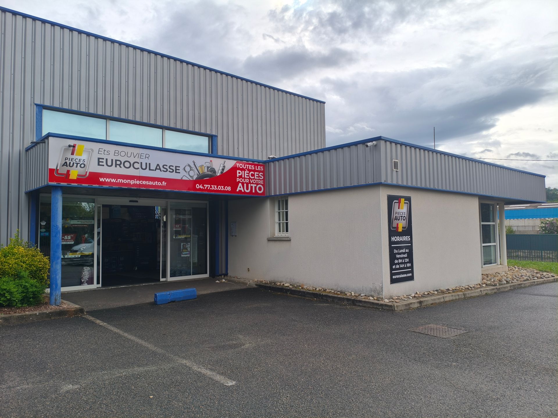 Magasin de pièces automobiles avec enseigne française et entrée vitrée donnant sur une rue ensoleillée