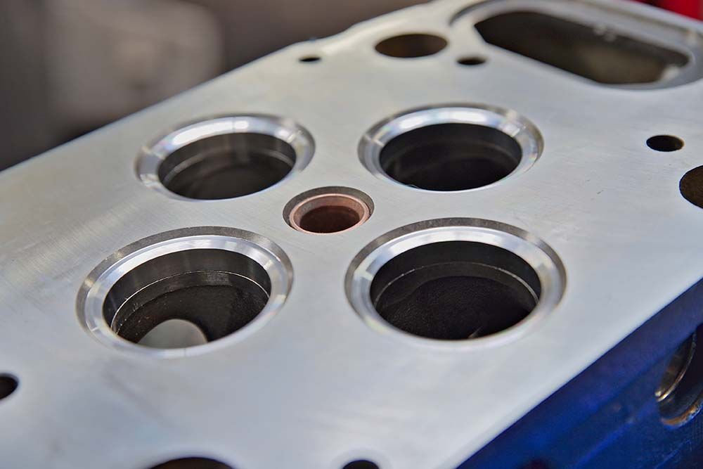 Gros plan sur une culasse de moteur en métal usiné avec de multiples ouvertures de soupapes circulaires.