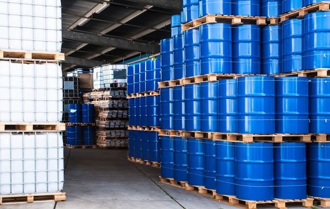 Un almacén lleno de barriles azules y blancos sobre paletas de madera.