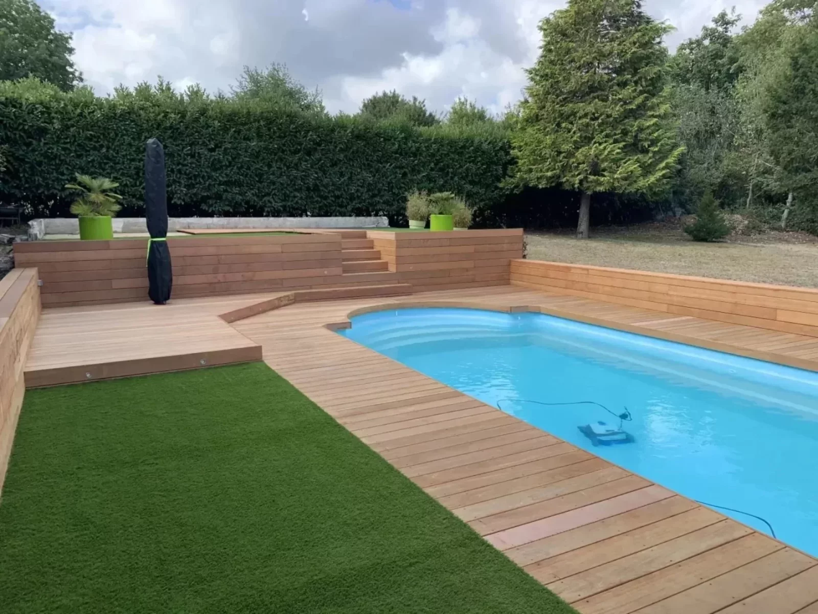 Une piscine entourée d'une terrasse en bois et sa margelle en bois