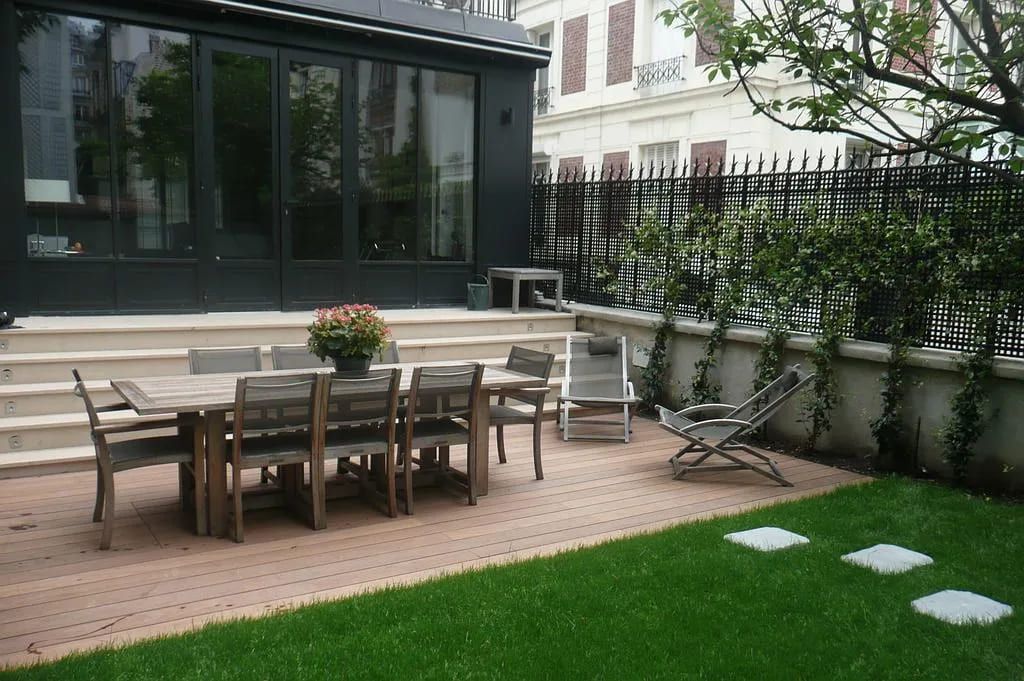Terrasse aménagée en bois devant une grande verrière de style industriel