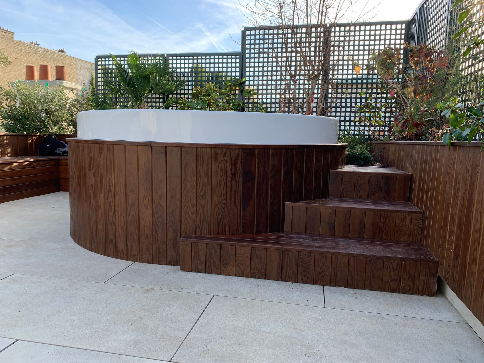 Un rooftop avec terrasse en pierre, pergola et claustras en bois