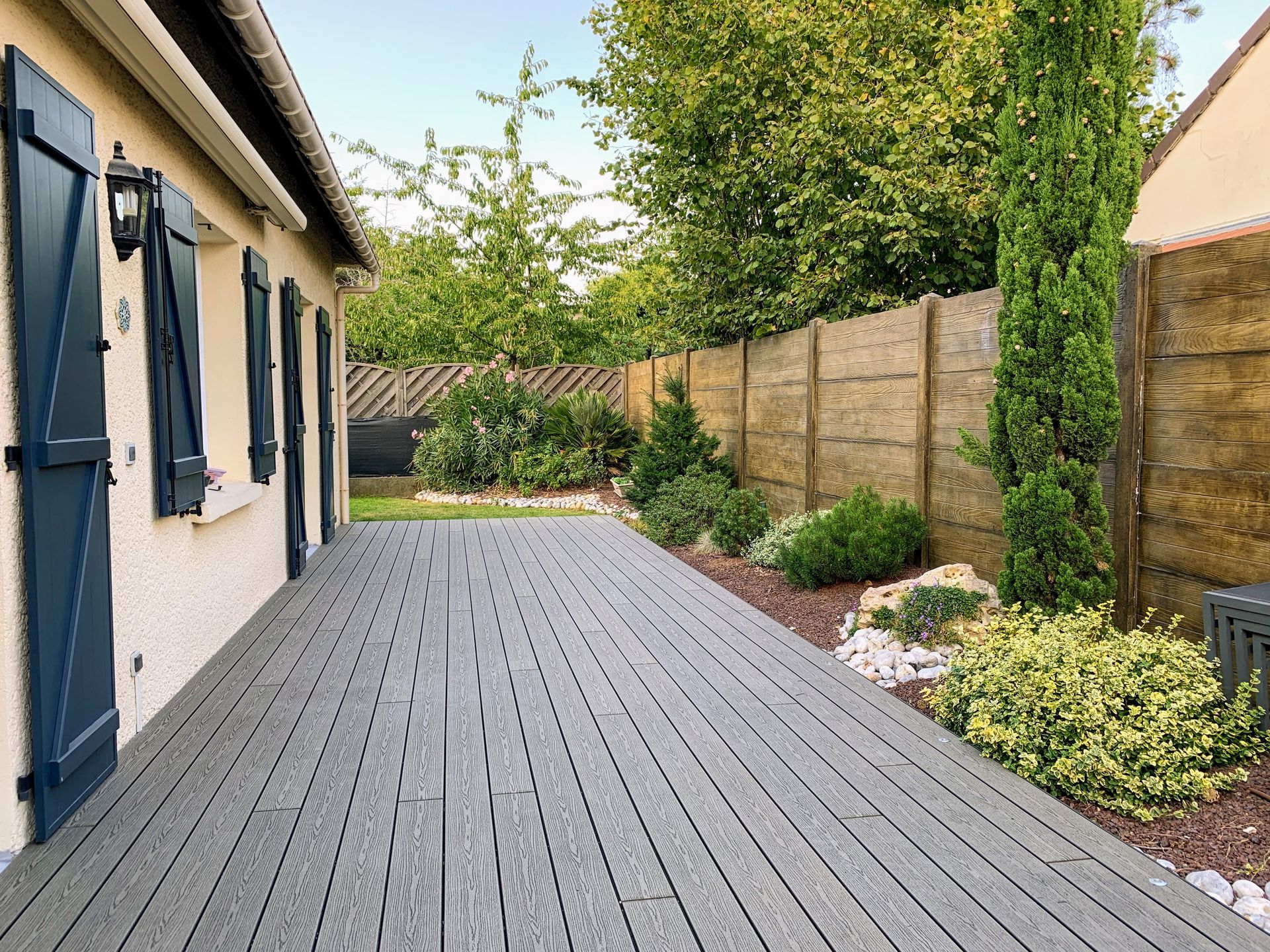 Terrasse végétalisée en bois avec table et chaises en teck foncé