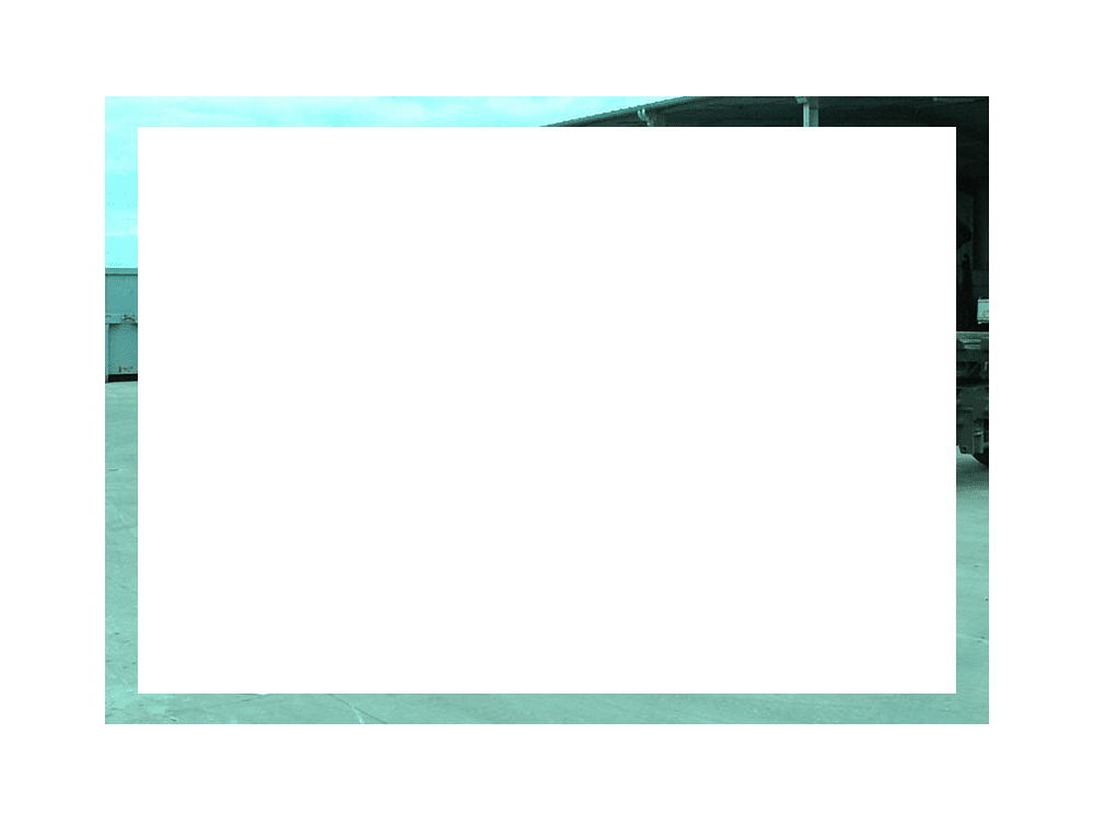 Rectangle blanc bordé d'un liseré bleu turquoise flou. En arrière-plan, on aperçoit une partie d'un bâtiment et le ciel.