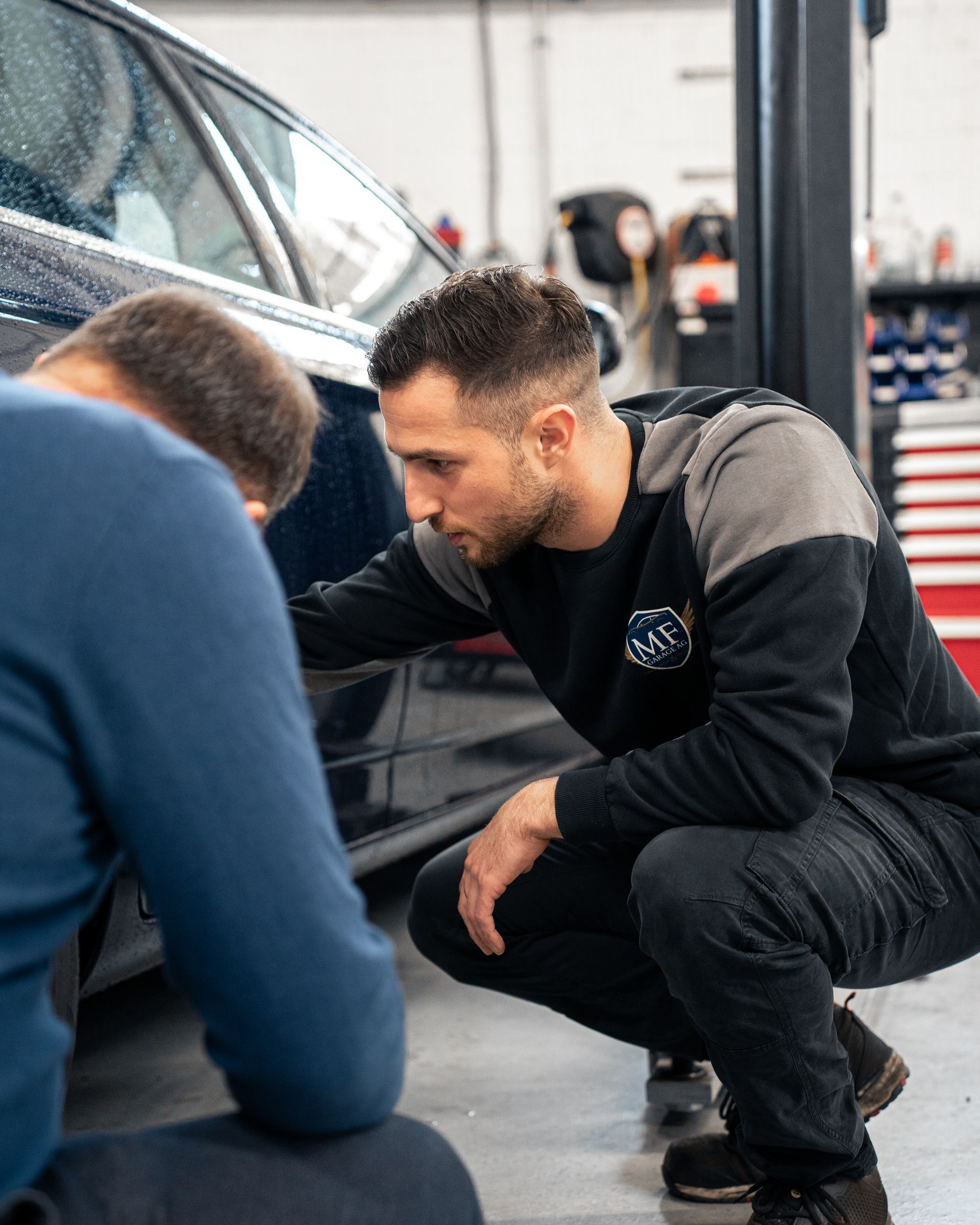 Ein Mann arbeitet in einer Garage an der Unterseite eines Autos.