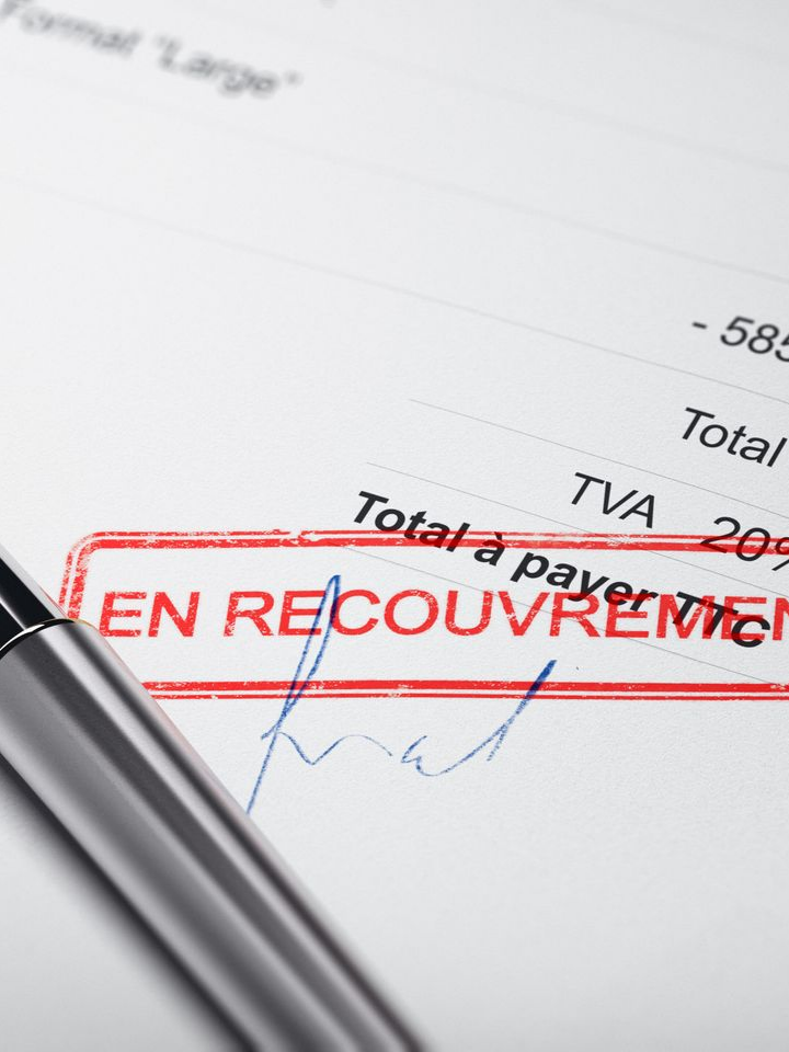 Gros plan sur un document portant un tampon rouge EN RECOUVREMENT.