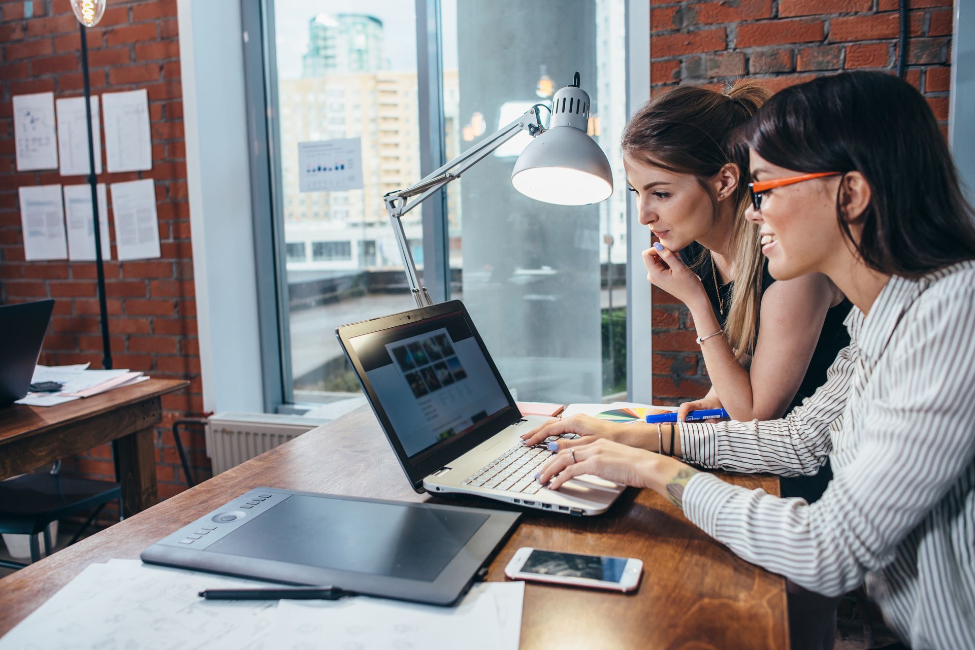 Deux femmes consultent un ordinateur portable dans un bureau.