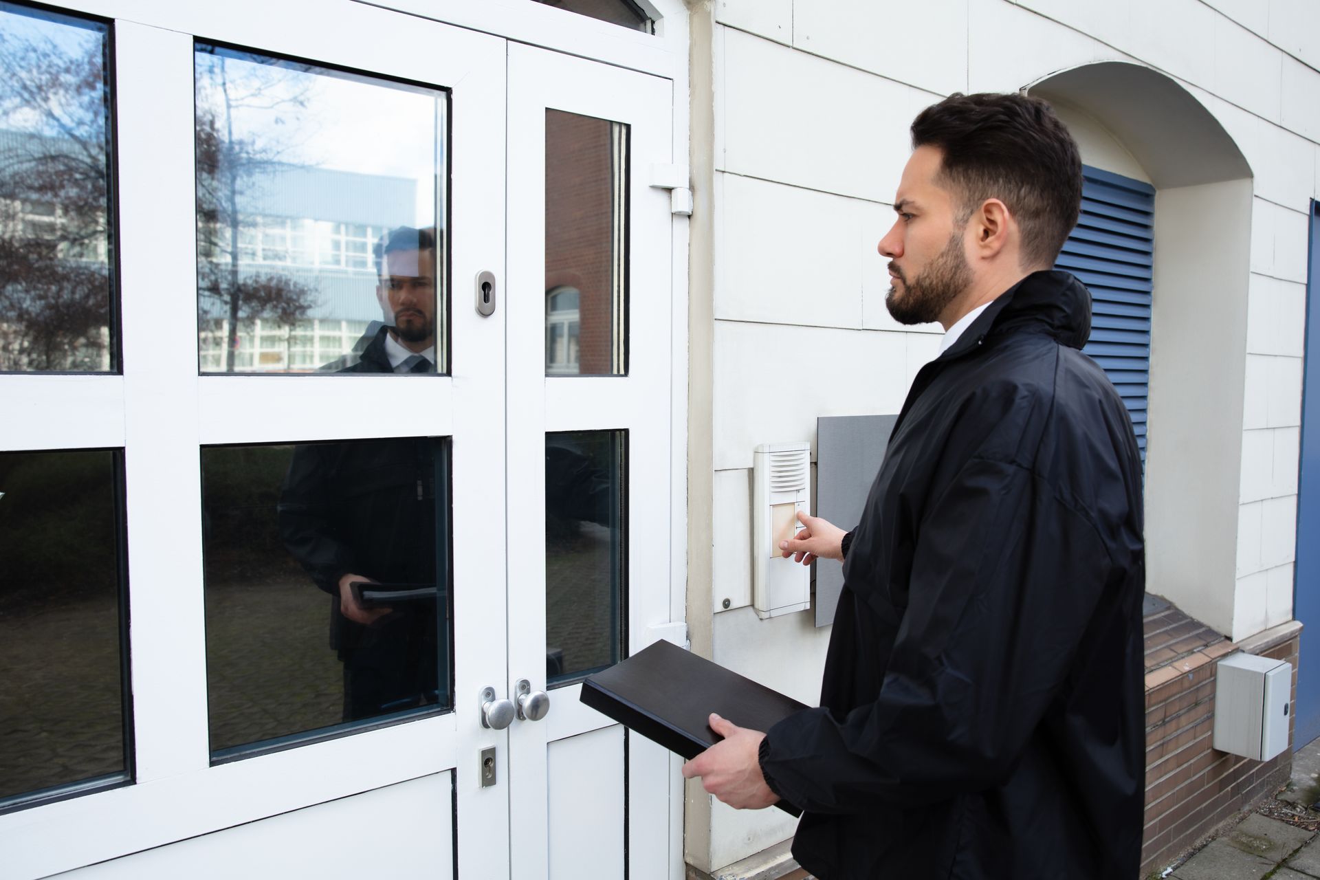 Un homme en veste noir, tenant un dossier.