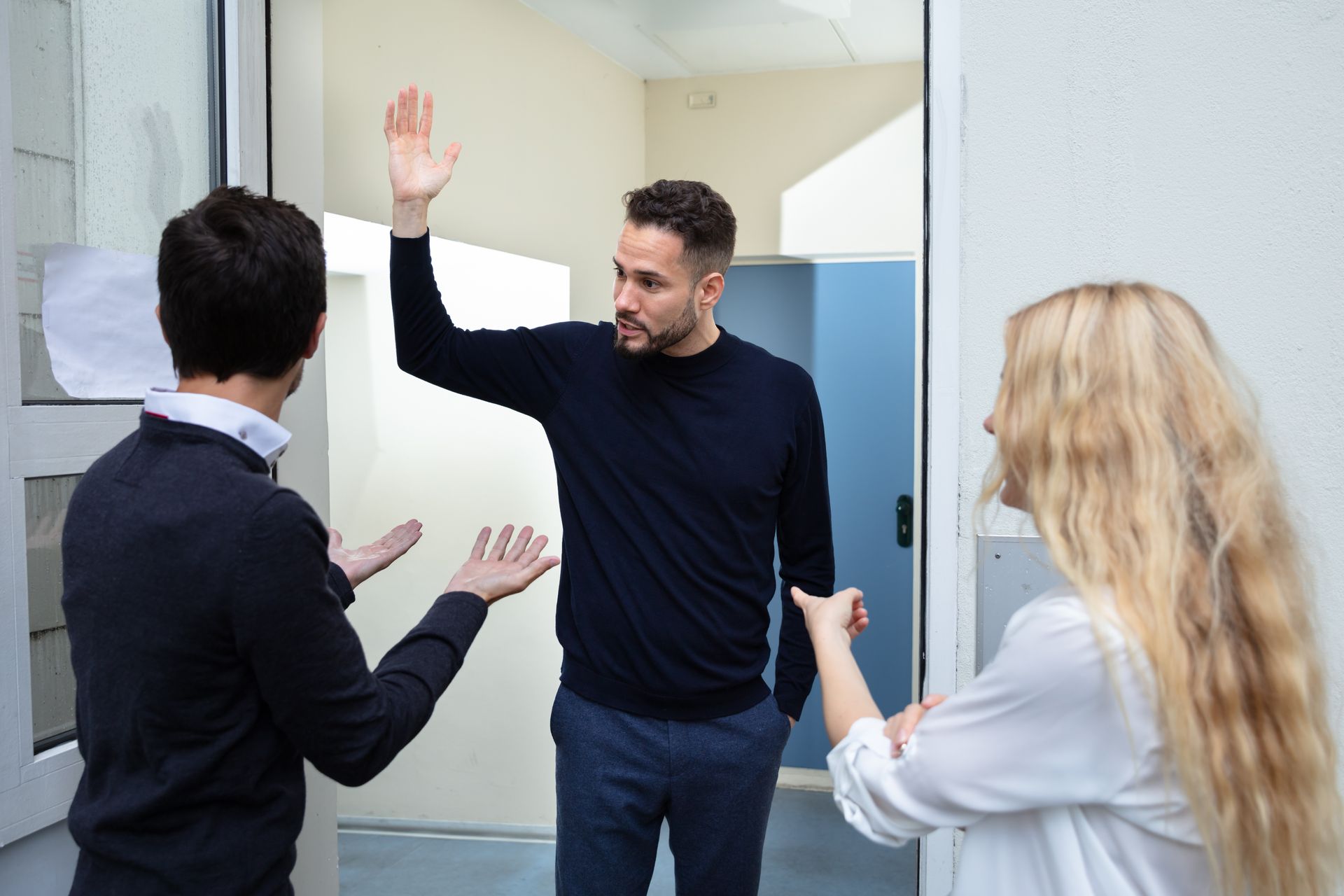 Trois personnes se disputent dans l'embrasure d'une porte.