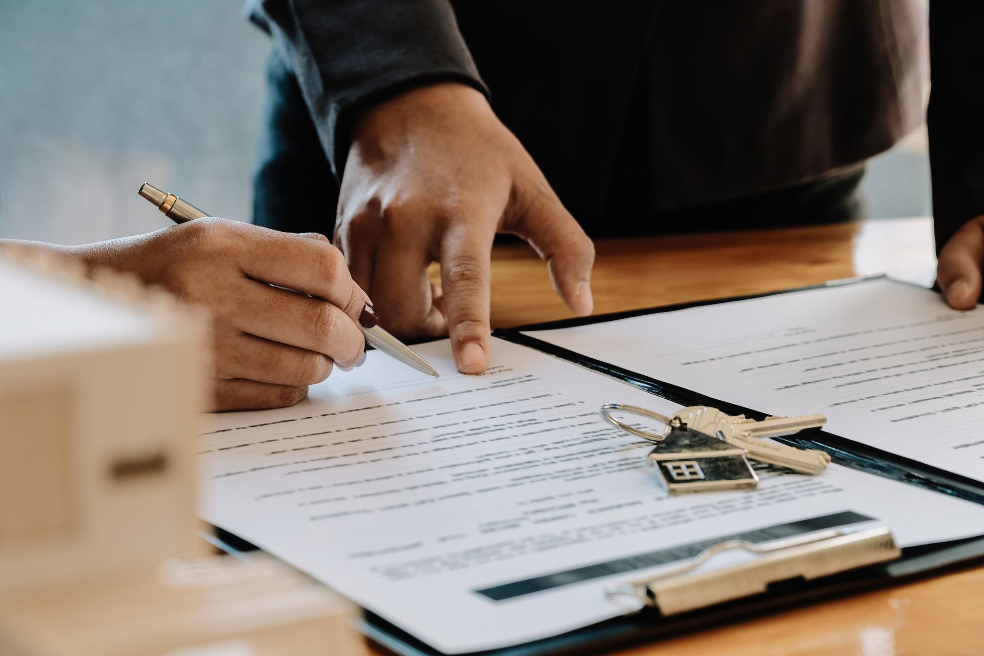 Des mains signant des documents immobiliers.
