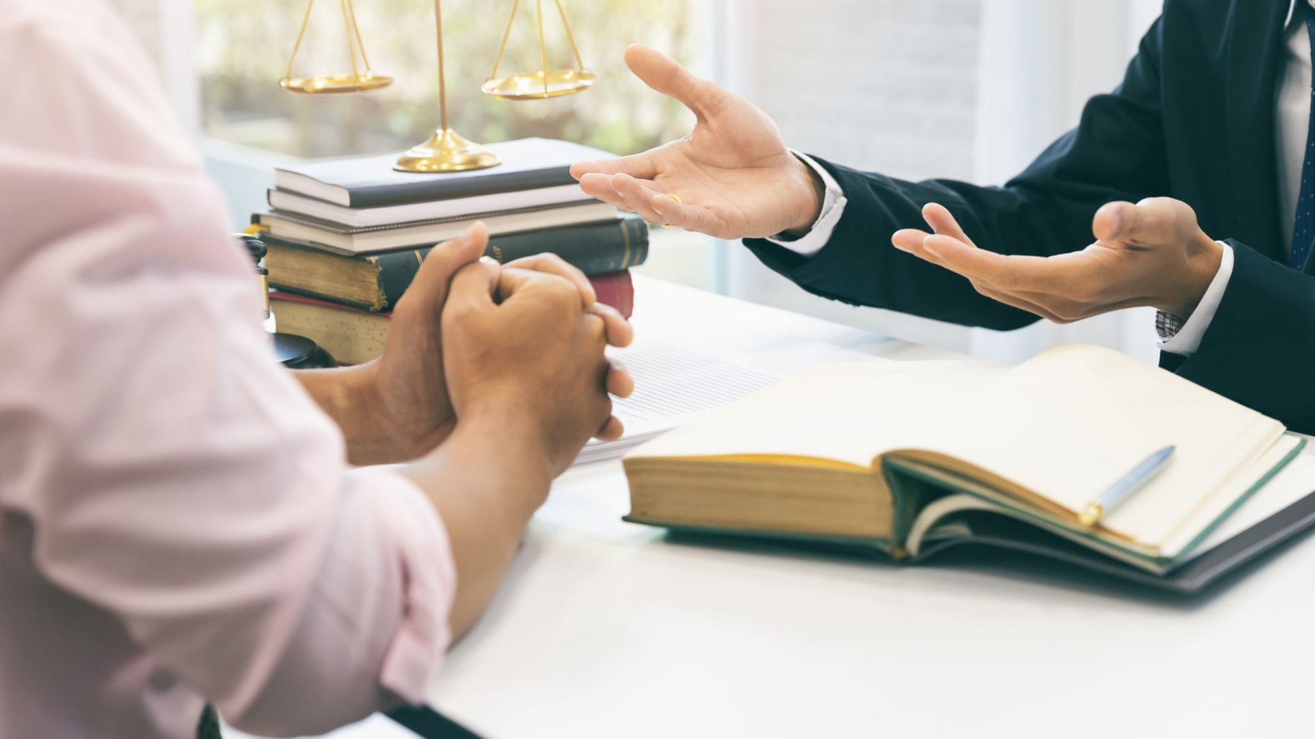 Un avocat fait des gestes, expliquant des documents à un client assis à un bureau.