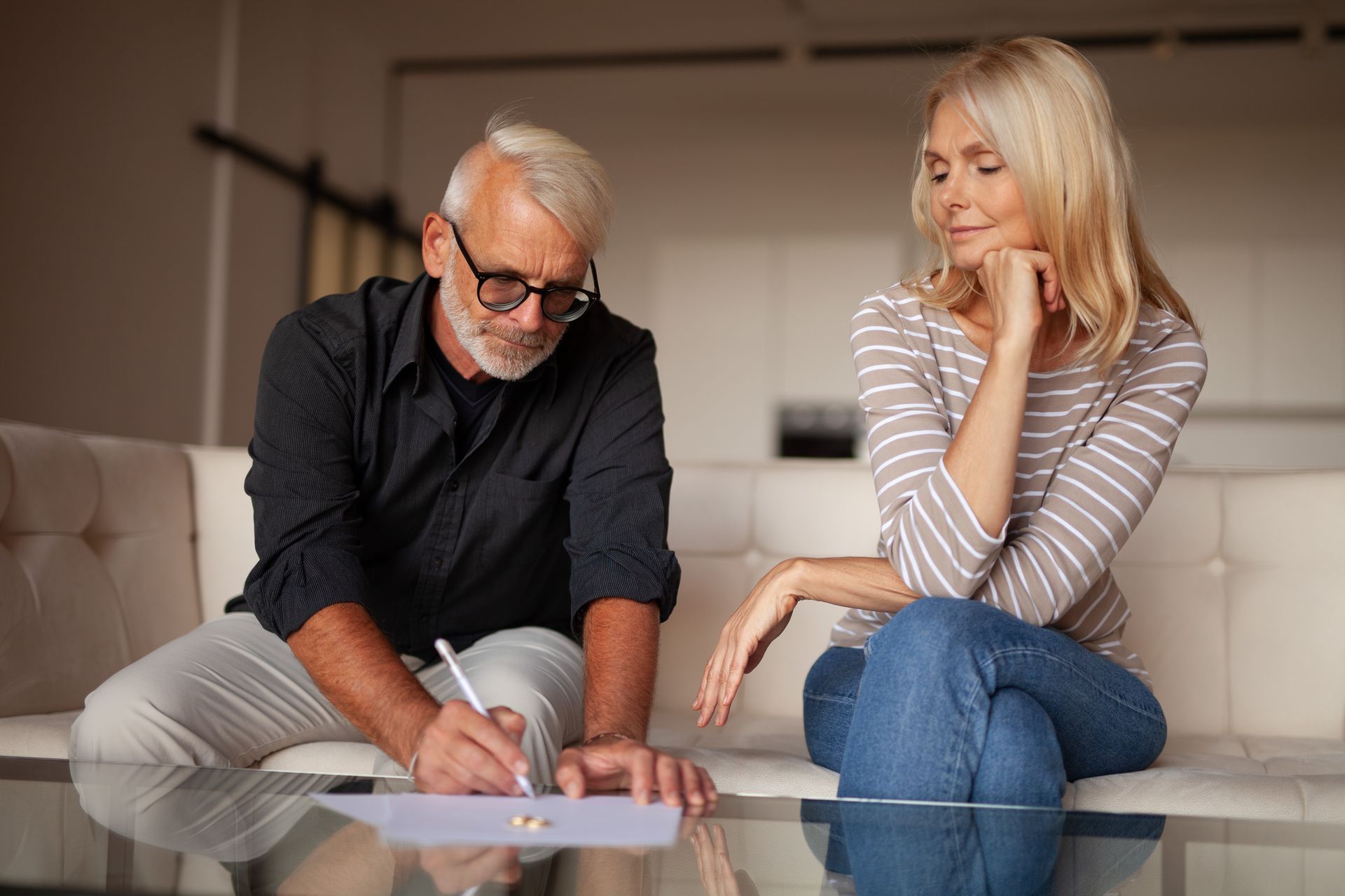 Un homme écrit sur une feuille de papier, une femme regarde.