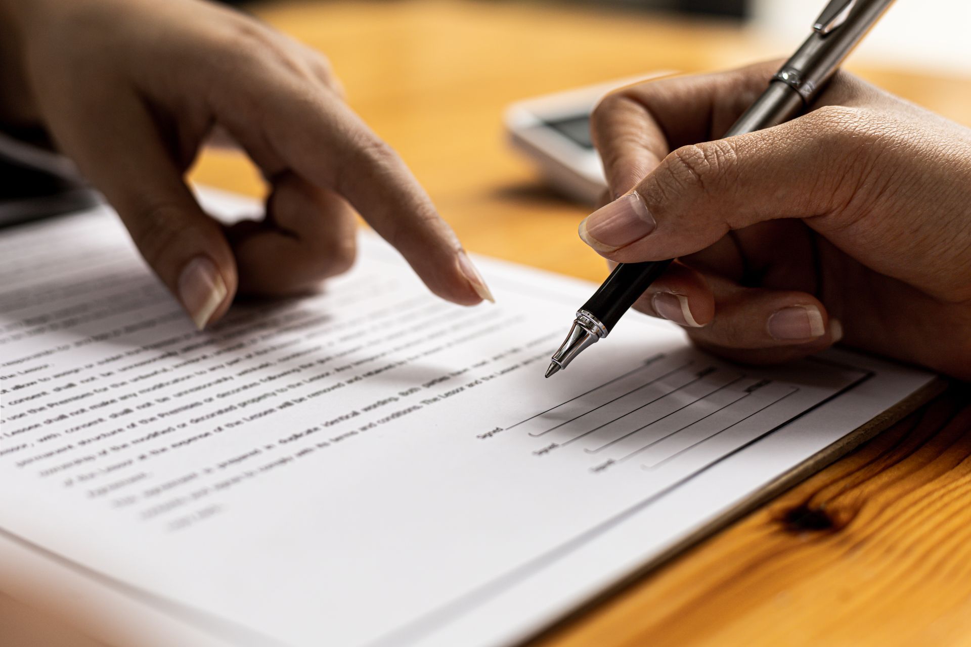 Une personne signe un document, une autre le désigne du doigt.