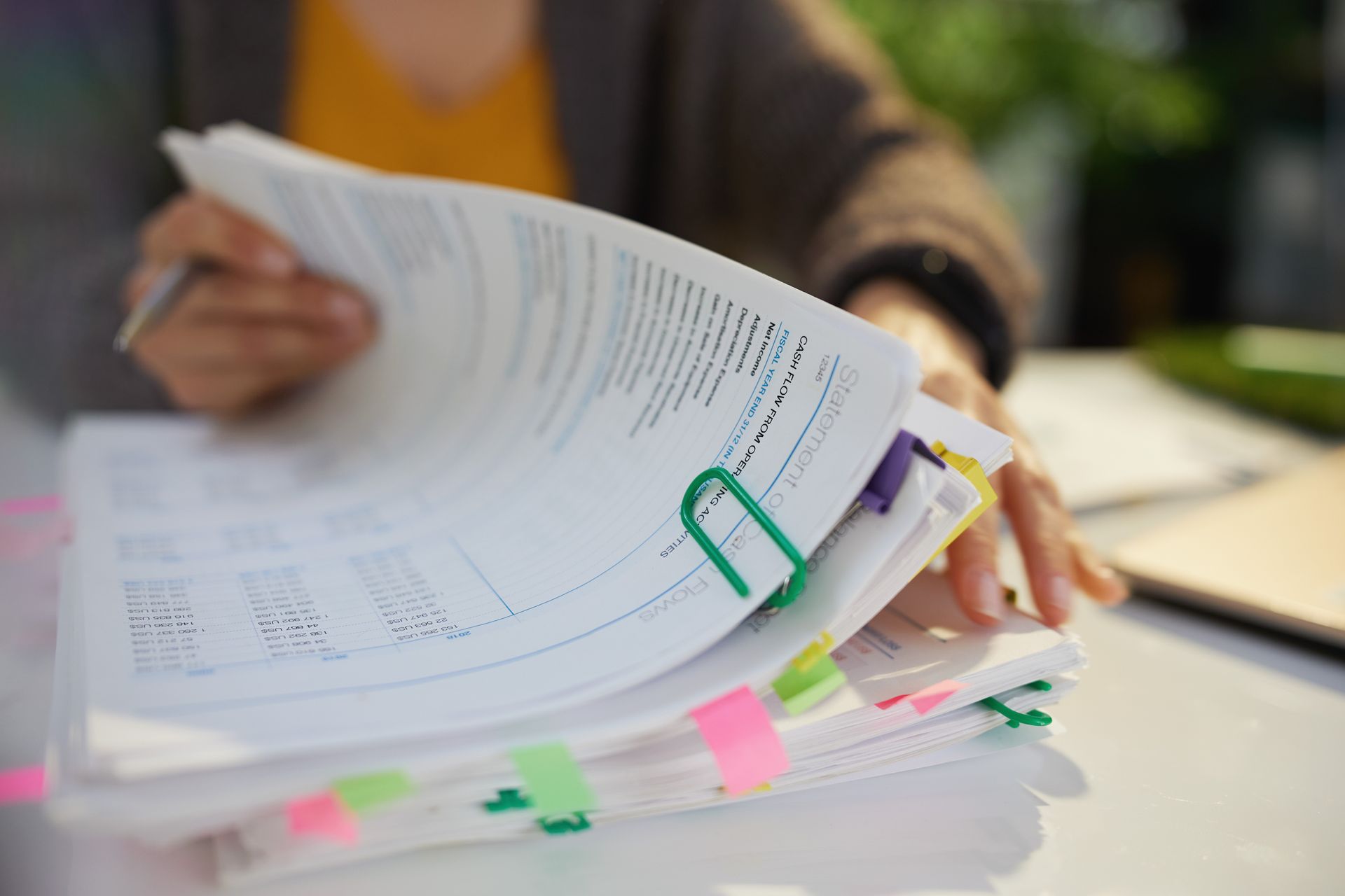 Une femme trie une pile de papiers avec des post-it et une pince à reliure.