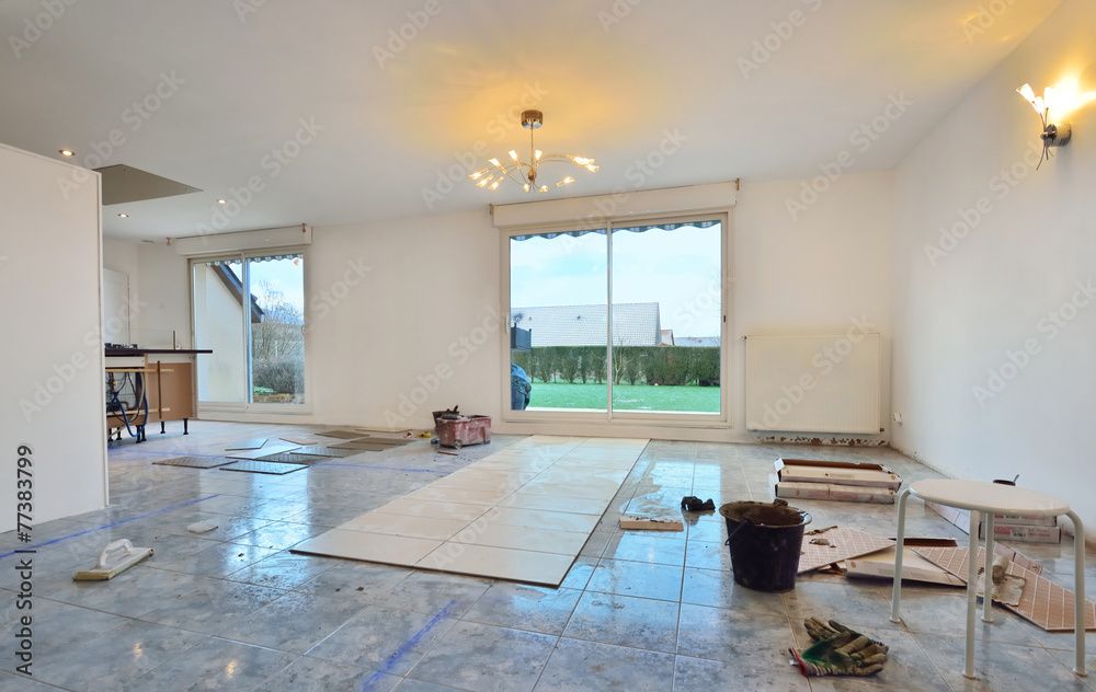 Une pièce en rénovation avec un sol carrelé, un grand espace central avec des carreaux neufs.