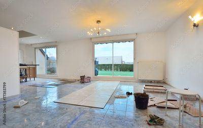 Une pièce en rénovation avec un sol carrelé, un grand espace central avec des carreaux neufs.