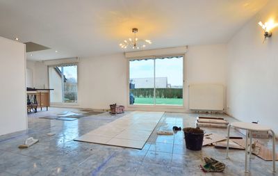 Une pièce en rénovation avec un sol carrelé, un grand espace central avec des carreaux neufs.