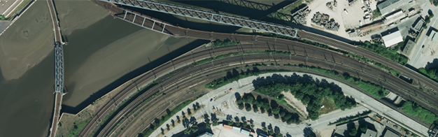 eine Luftaufnahme einer Bahnstrecke und einer Brücke.
