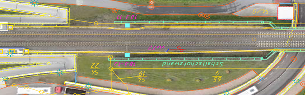 eine Luftaufnahme einer Bahnstrecke und einer Straße.