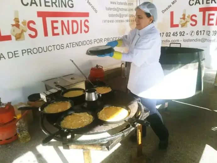 Una mujer está preparando comida frente a un cartel que dice catering.