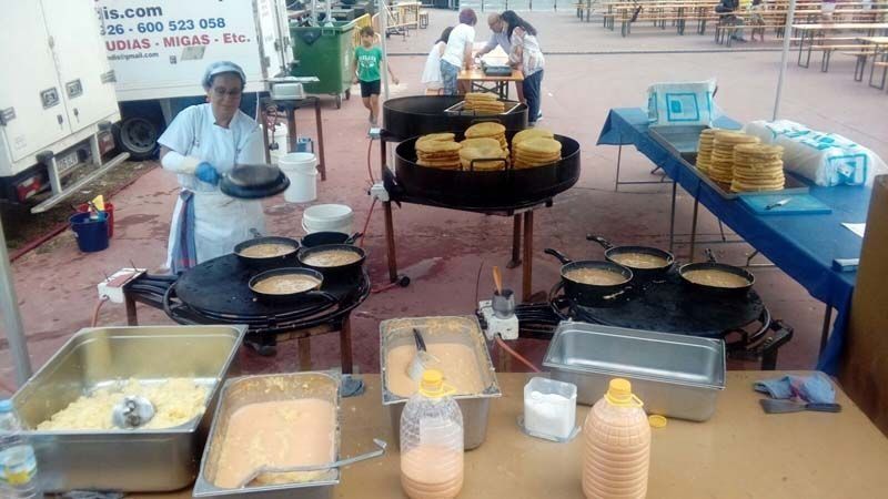 Un grupo de personas está preparando comida en una mesa al aire libre.