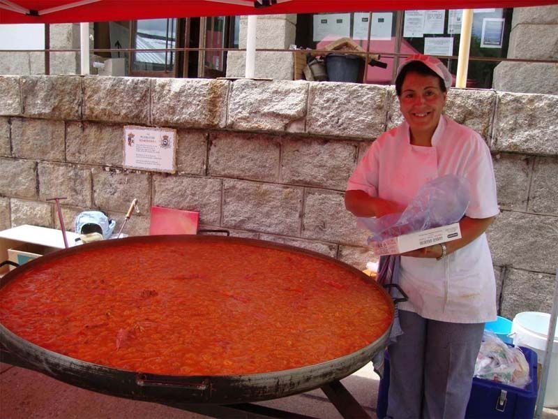 Una mujer está parada frente a una gran sartén con comida.