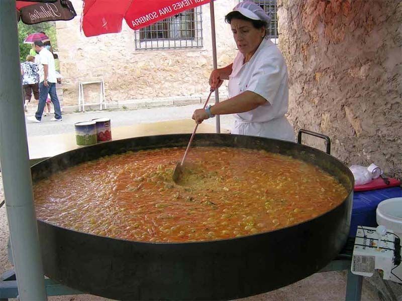 Una mujer está revolviendo una olla grande de comida con una cuchara.