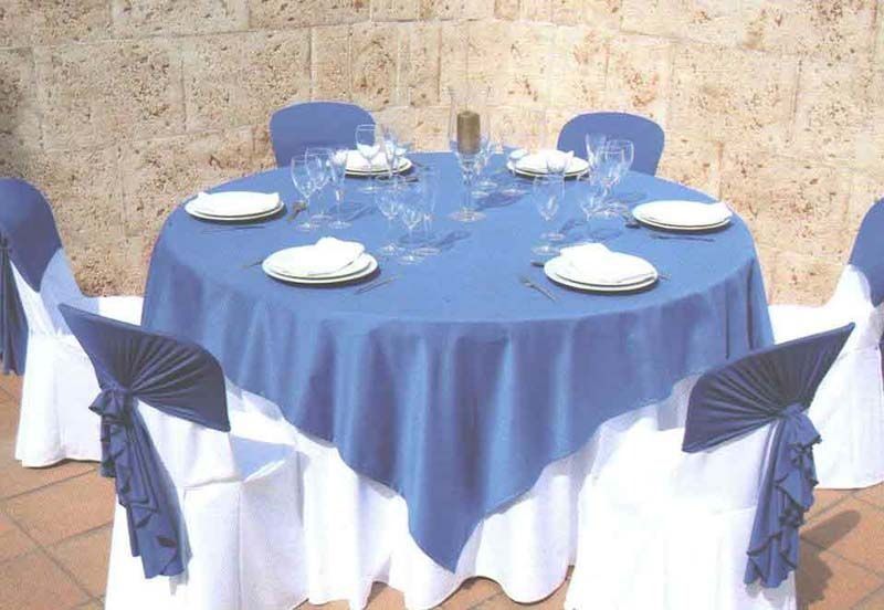 Una mesa redonda con un mantel azul y sillas blancas.