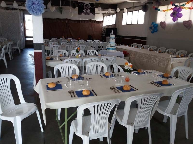 Una sala con mesas y sillas preparadas para una fiesta.