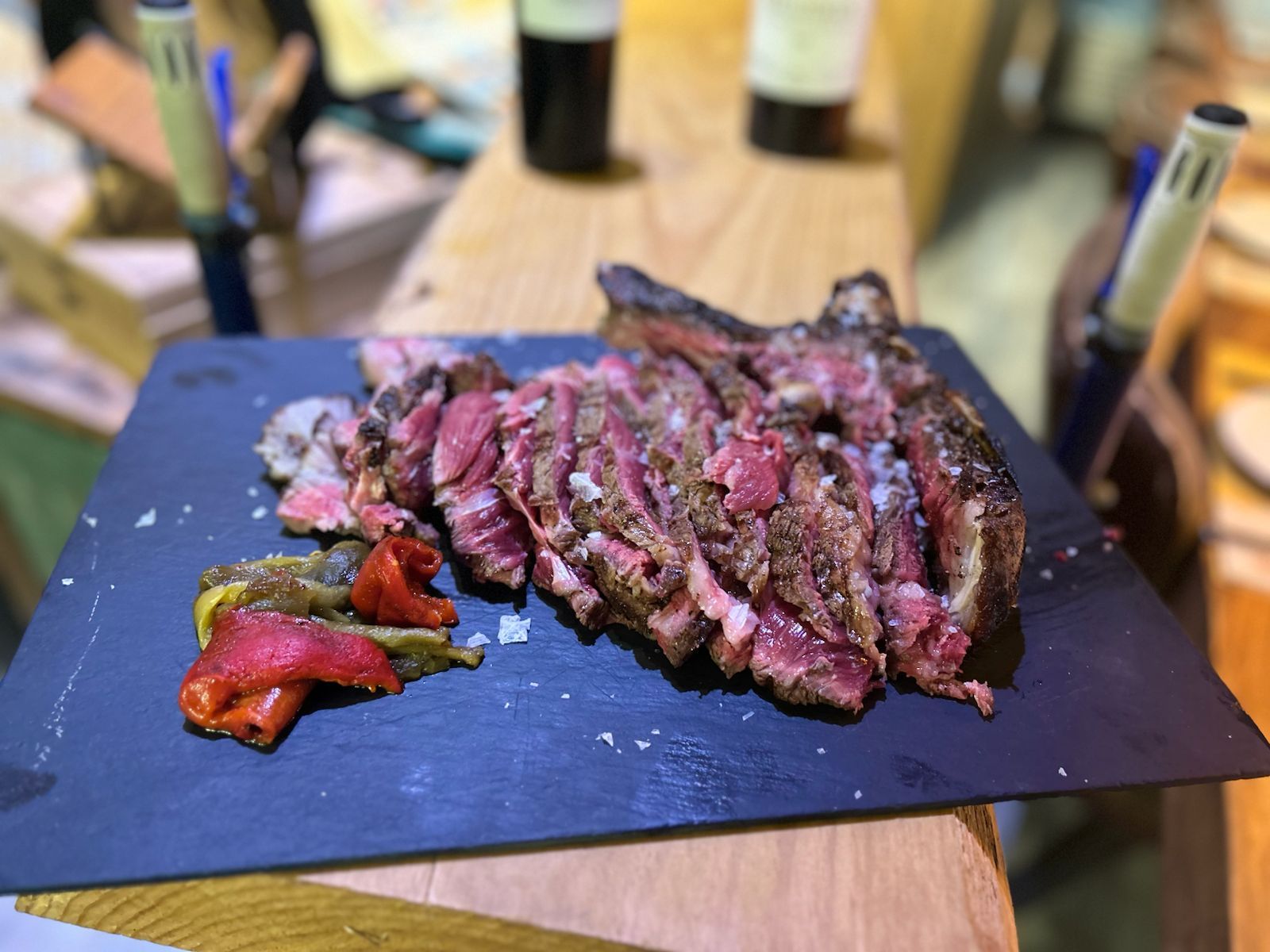 Filete rebanado con sal y pimientos asados sobre pizarra negra.