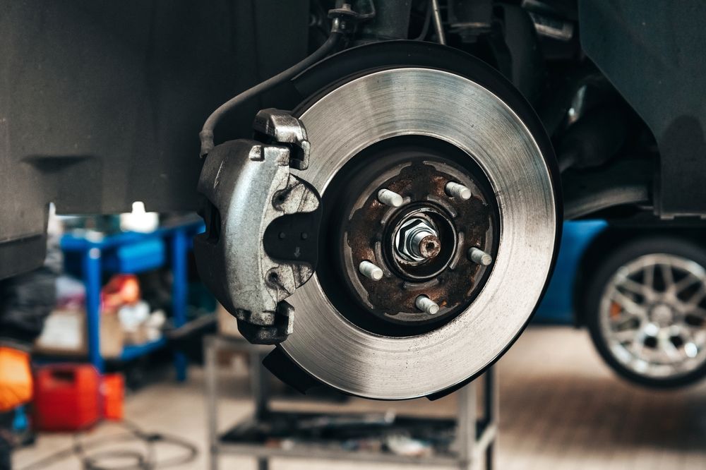 En un taller mecánico profesional se puede ver el conjunto del disco de freno y la pinza de freno de un coche.