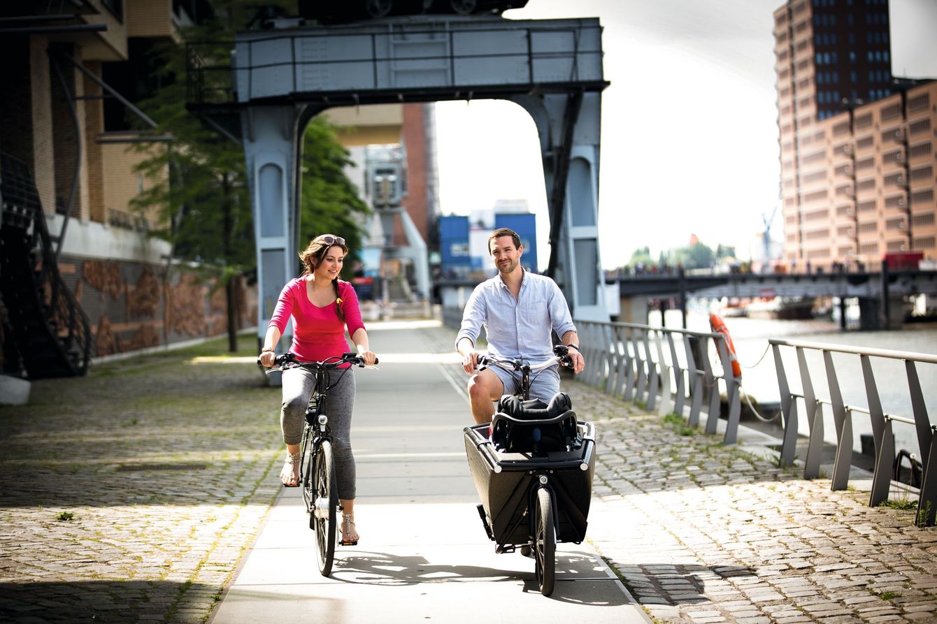 Ein Mann und eine Frau fahren auf einem Bürgersteig Fahrrad.