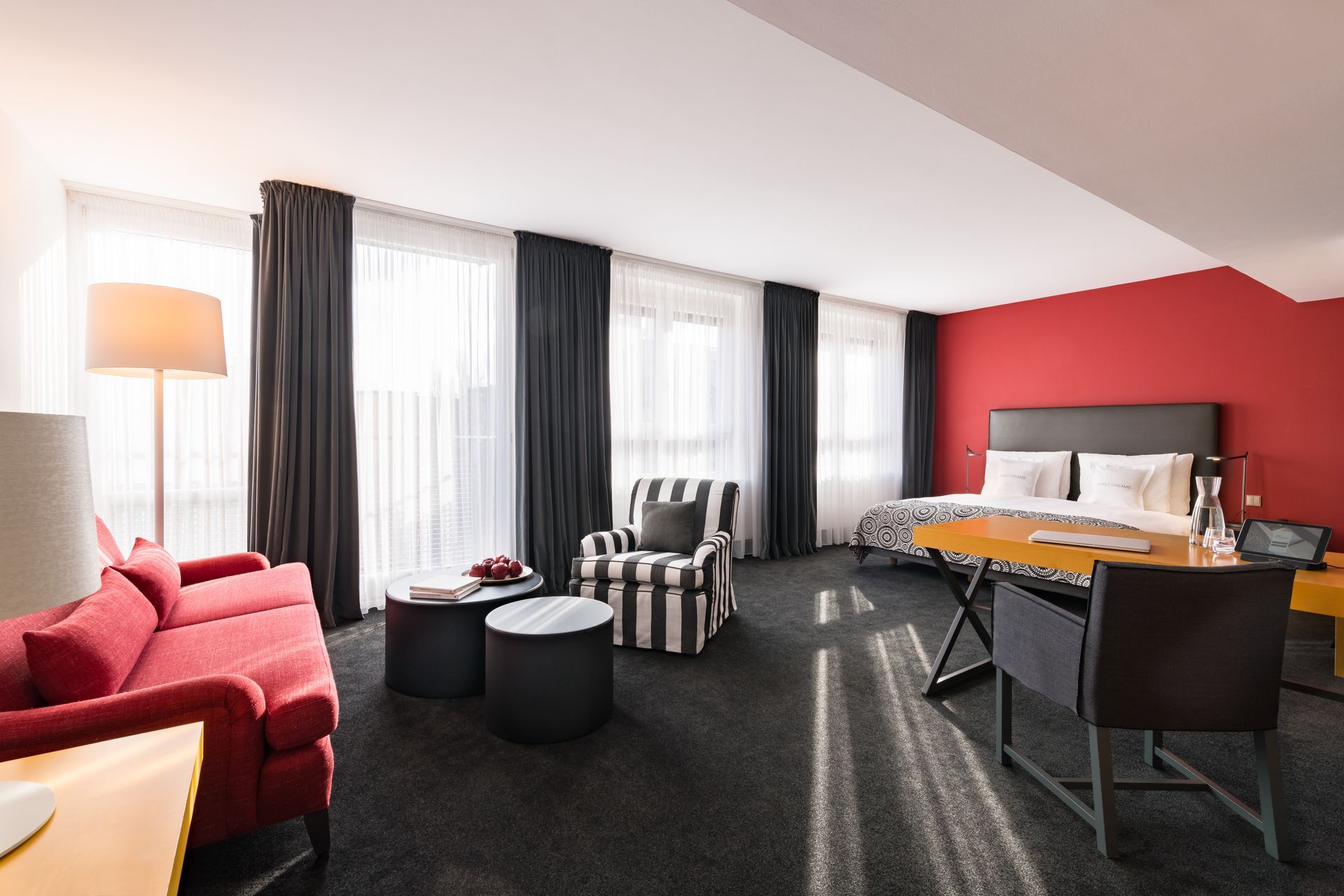 Ein Hotelzimmer mit Couch, Sessel, Schreibtisch und Bett.