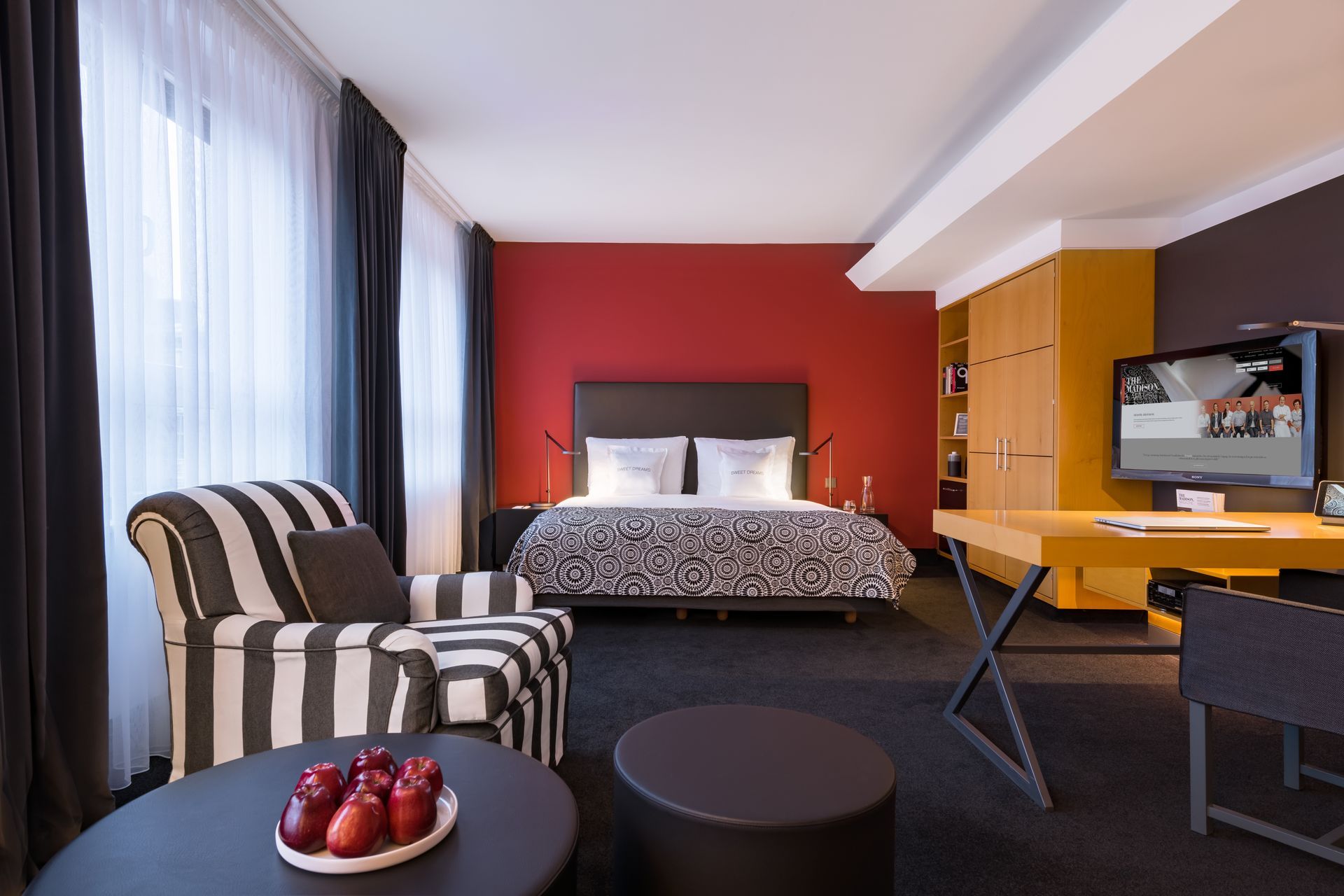 Ein Hotelzimmer mit Bett, Stuhl, Tisch und Fernseher