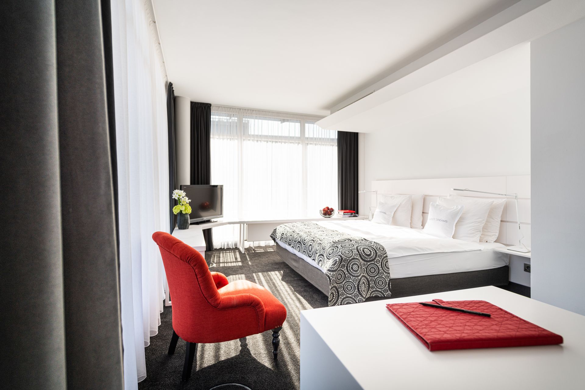 A hotel room with a large bed and a red chair