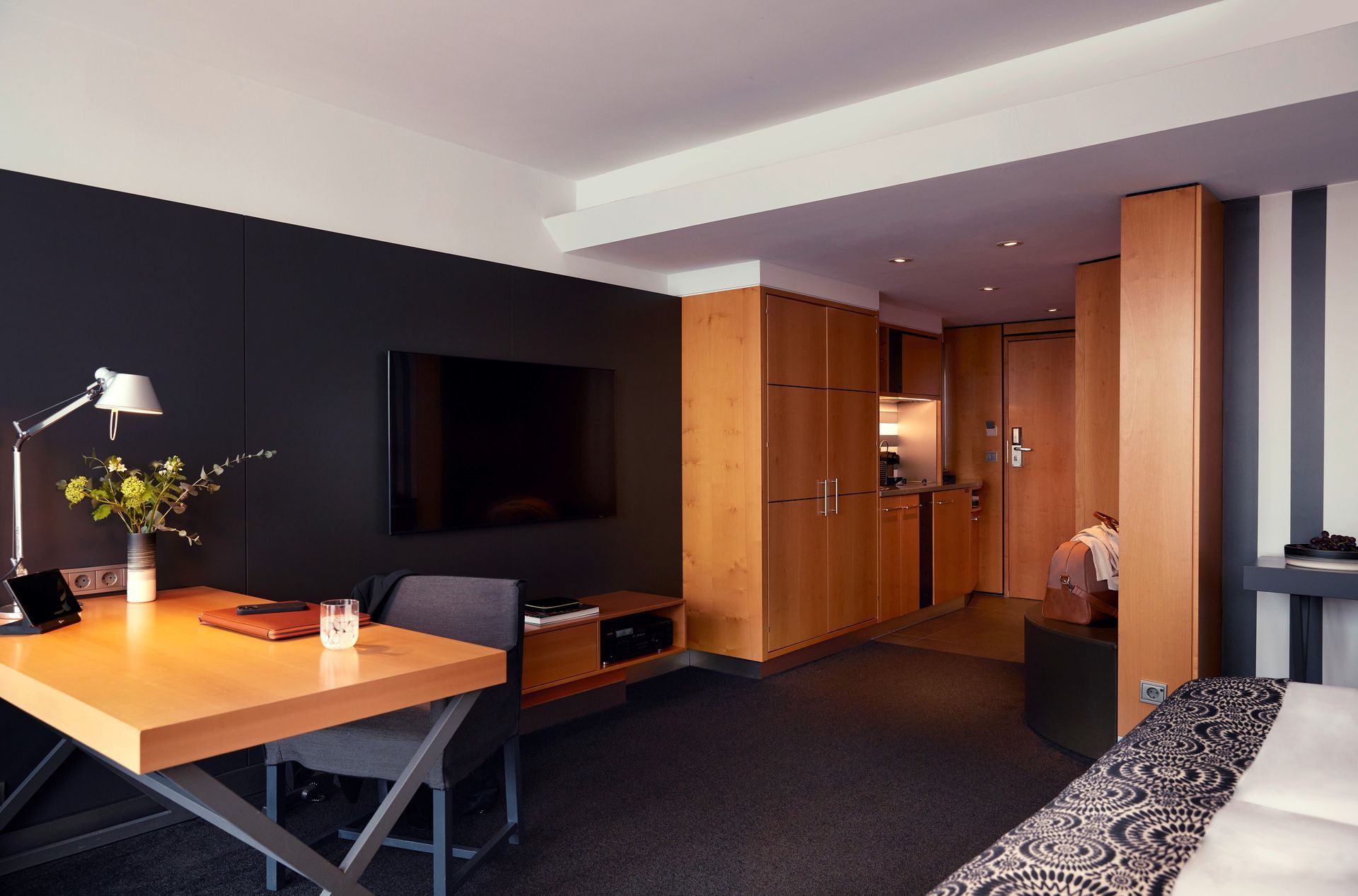 A hotel room with a desk and a flat screen tv